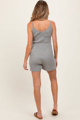 woman wearing a gray ribbed maternity romper with adjustable straps, showing her back and legs