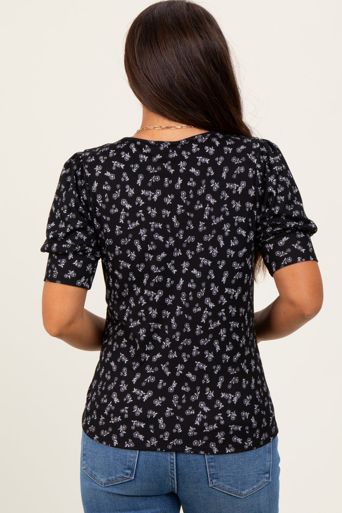 woman wearing a black maternity top with floral print and short puff sleeves, seen from the back
