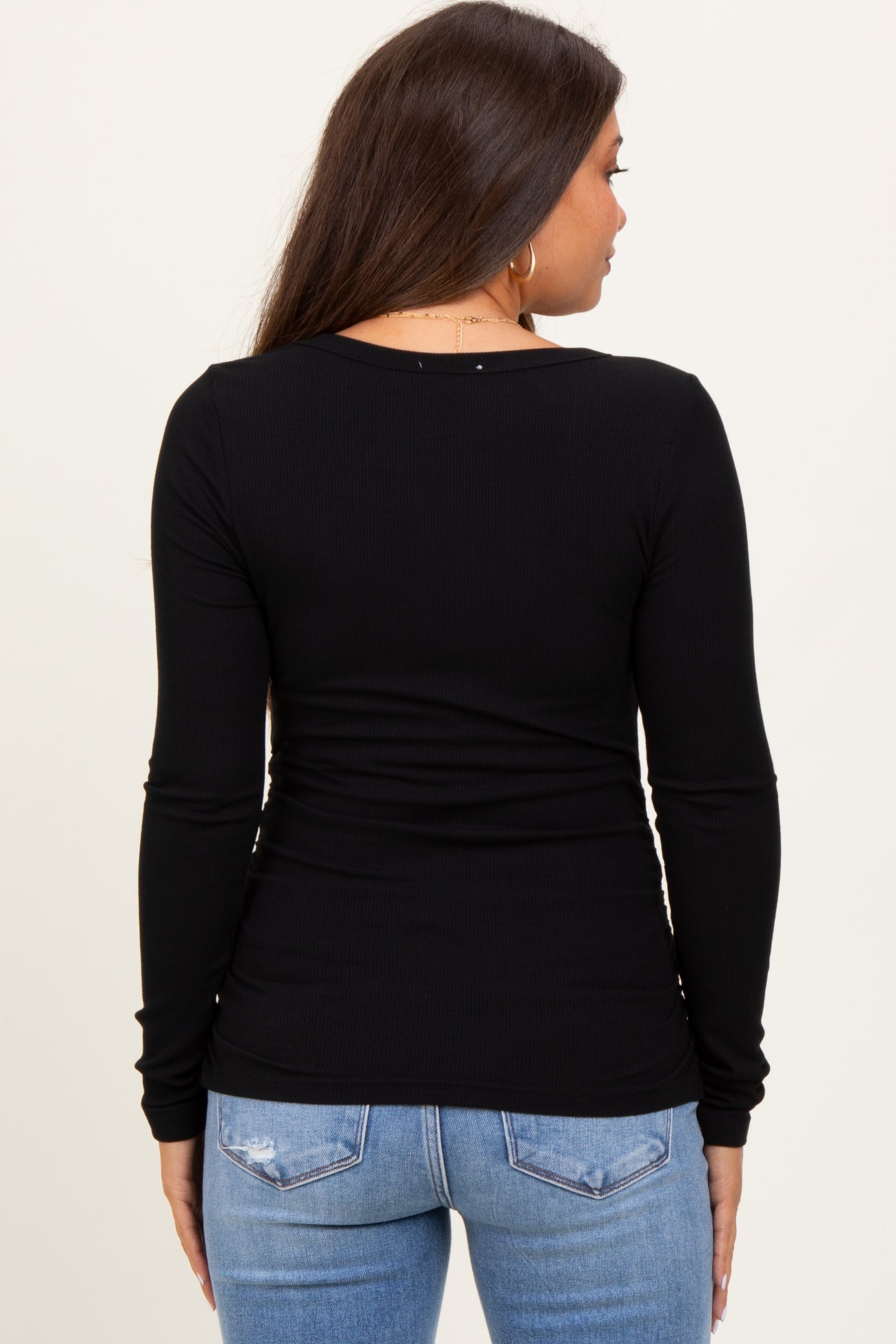 woman wearing a black long sleeve maternity top, seen from the back, paired with light blue jeans