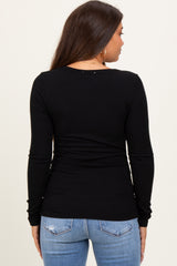 woman wearing a black long sleeve maternity top, seen from the back, paired with light blue jeans