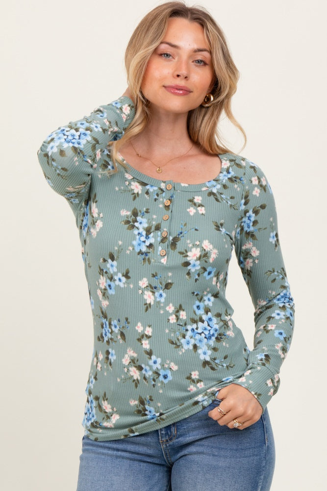 woman wearing a green floral long sleeve top with a scoop neckline and button details, paired with blue jeans