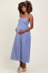 woman wearing a blue patterned maternity maxi dress with a visible baby bump and styled curly hair