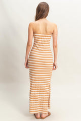 woman wearing a striped strapless maxi dress in orange and cream colors, standing with her back to the camera