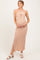 woman wearing a striped maternity maxi dress in peach and white, holding her baby bump and smiling