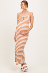 woman wearing a striped maternity maxi dress in peach and white, gently cradling her baby bump