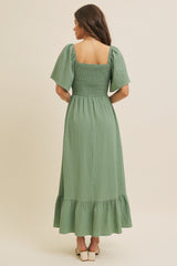 woman wearing a green smocked back maxi dress with short puff sleeves and a ruffled hem