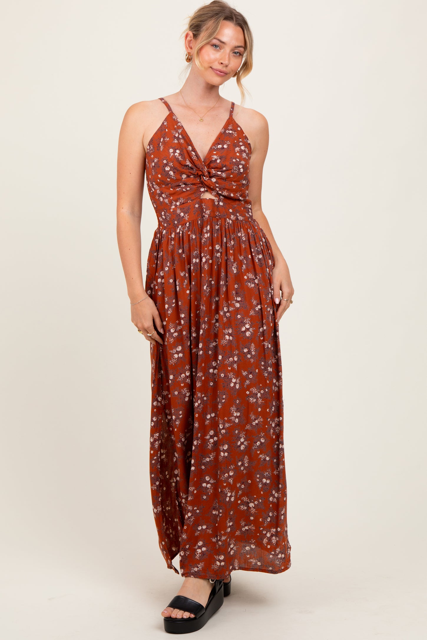 woman wearing a rust floral maxi dress with a knotted front and spaghetti straps
