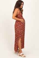 woman wearing a rust floral maternity maxi dress with a side slit and holding her baby bump