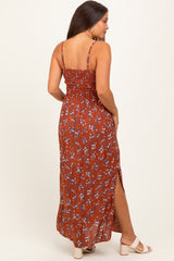 woman wearing a rust-colored floral maternity maxi dress with a smocked bodice and side slits