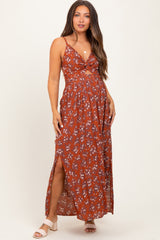 woman wearing a rust floral maternity maxi dress with side slits and a front tie detail, showing her baby bump