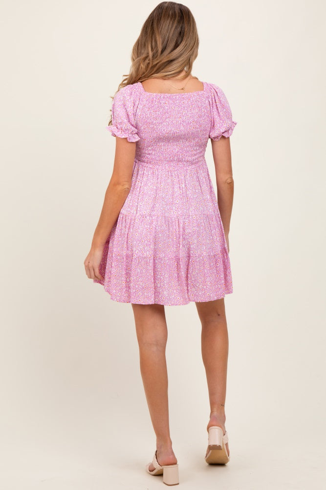 woman wearing a pink floral maternity dress with puff sleeves and a fitted bodice, showing a baby bump from behind