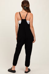 woman wearing a black sleeveless jumpsuit with adjustable straps and a relaxed fit from the back