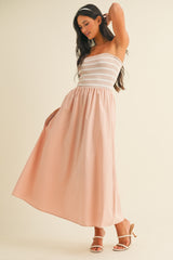 woman wearing a strapless pink maxi dress with a smocked bodice and flowy skirt