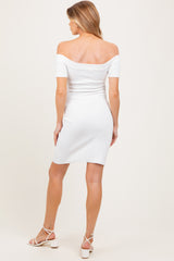 woman wearing a white off-the-shoulder maternity dress, showing a fitted style from the back