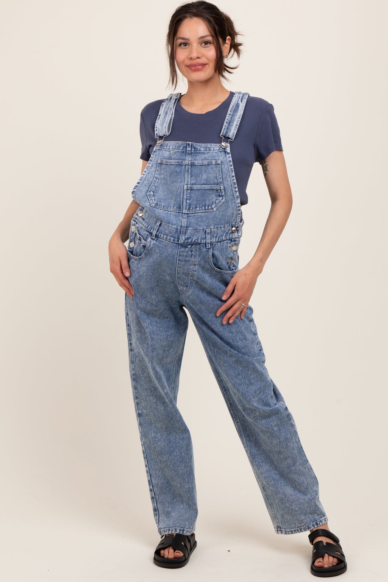 woman wearing a blue denim maternity overall with a relaxed fit and a dark blue t-shirt underneath