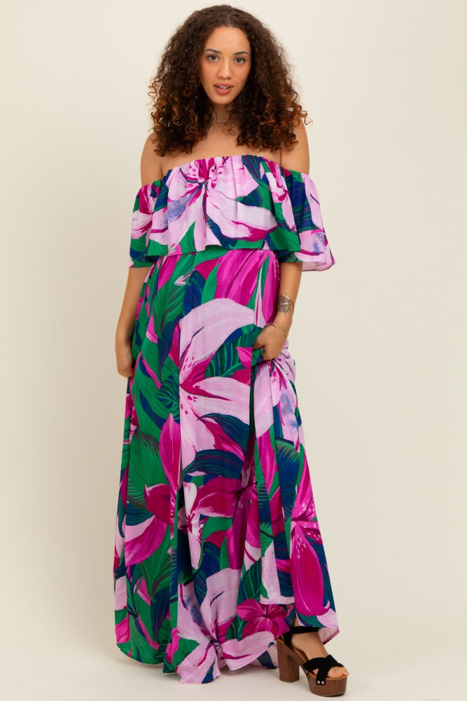 woman wearing a vibrant off-shoulder floral maxi dress in pink and green, with a flowing skirt and pockets, showcasing a baby bump