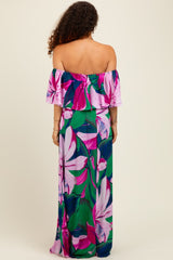 woman wearing a vibrant floral off-the-shoulder maxi dress in pink and green, showcasing the back view and flowing style