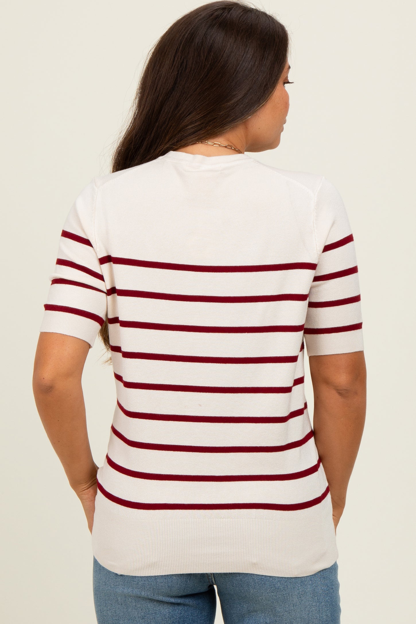woman wearing a cream and burgundy striped maternity top, showing a relaxed fit and short sleeves from the back