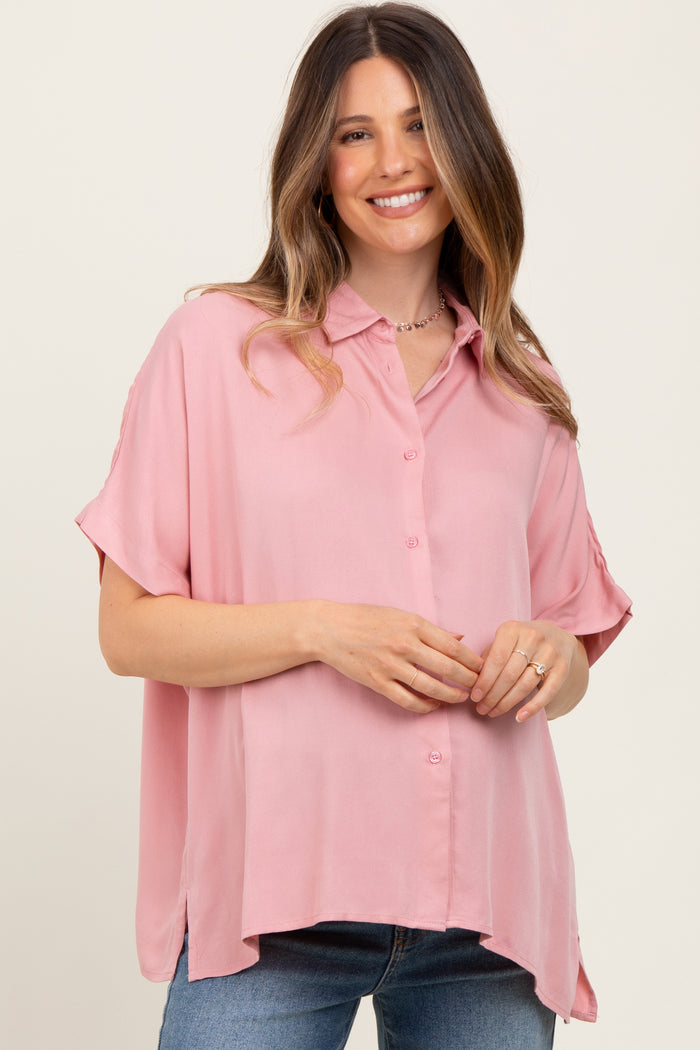 woman wearing a light pink short sleeve button-up maternity top with a relaxed fit and a visible baby bump