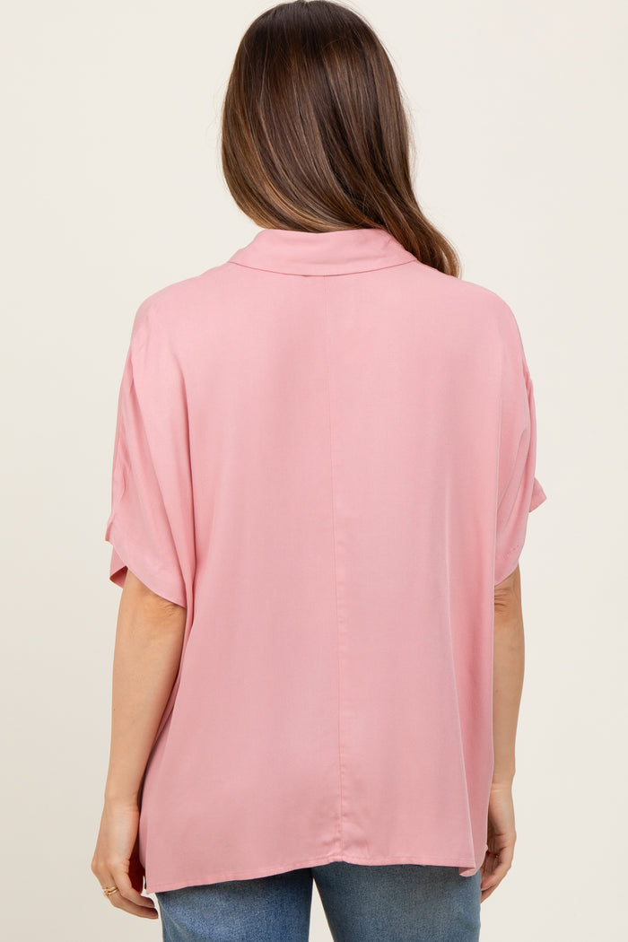 woman wearing a light pink maternity blouse with short sleeves, showing the back view