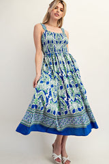 woman wearing a blue and green floral maxi dress with square neckline and smocked bodice, standing in a relaxed pose