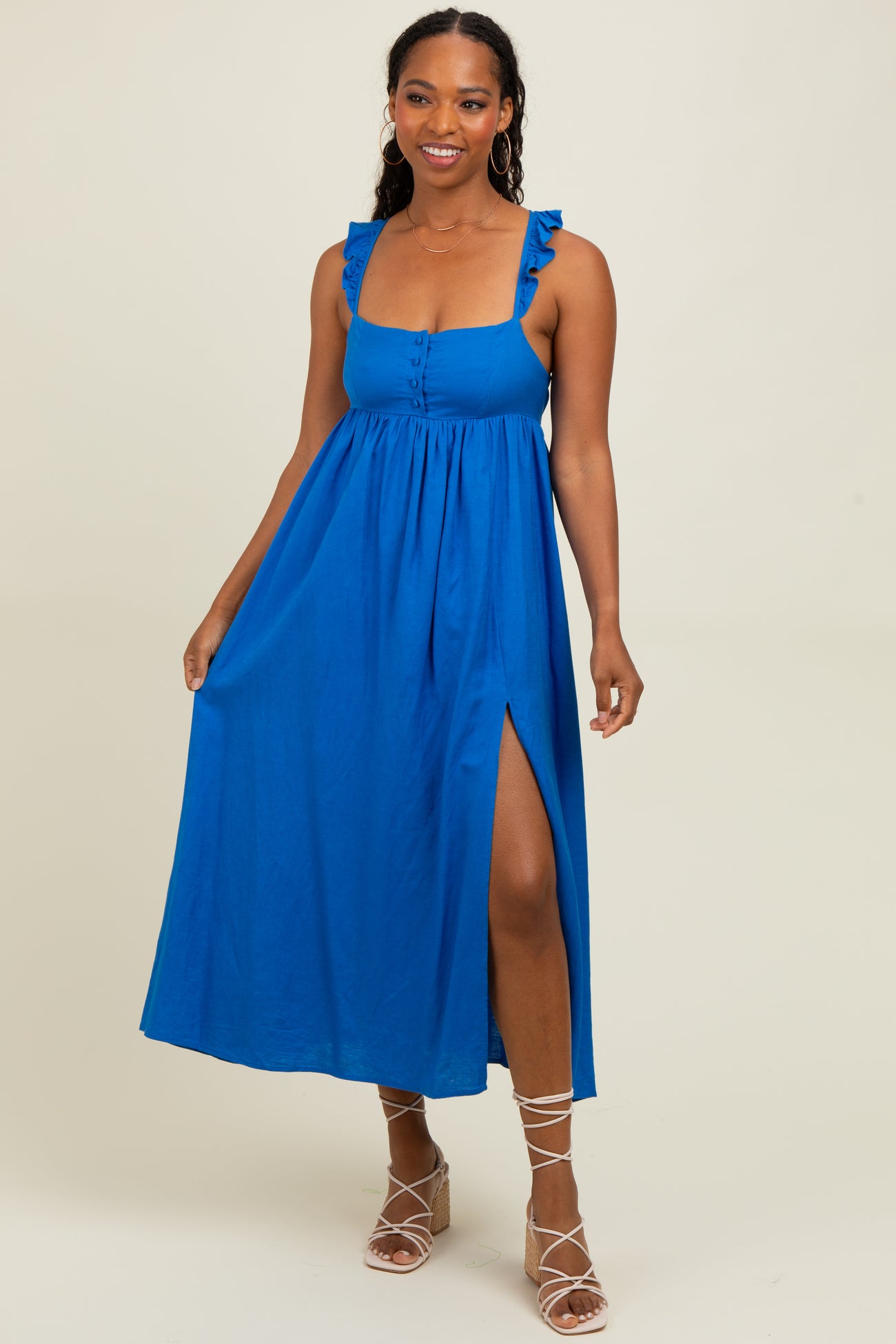 woman wearing a bright blue maxi dress with ruffled straps and a thigh-high slit