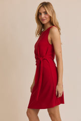 woman wearing a red sleeveless dress with a front tie detail and a flared skirt