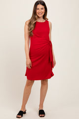 woman wearing a red maternity dress with a side tie detail and a flattering silhouette, styled with black sandals