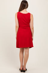 woman wearing a red sleeveless maternity dress with a flared skirt, seen from the back