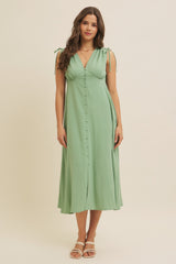 woman wearing a light green midi dress with tie straps and button details on the front