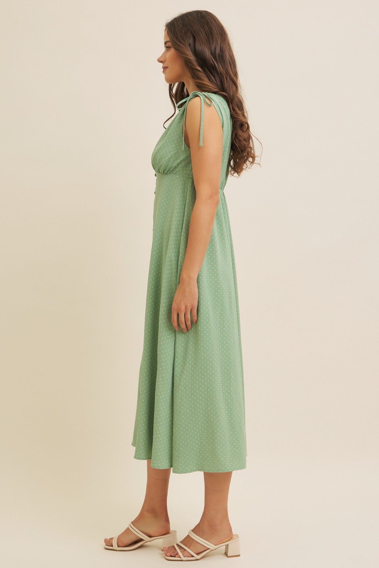 woman wearing a green dotted midi dress with tie shoulder straps and a flowy skirt