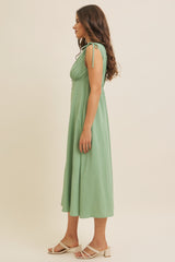 woman wearing a green dotted midi dress with tie shoulder straps and a flowy skirt