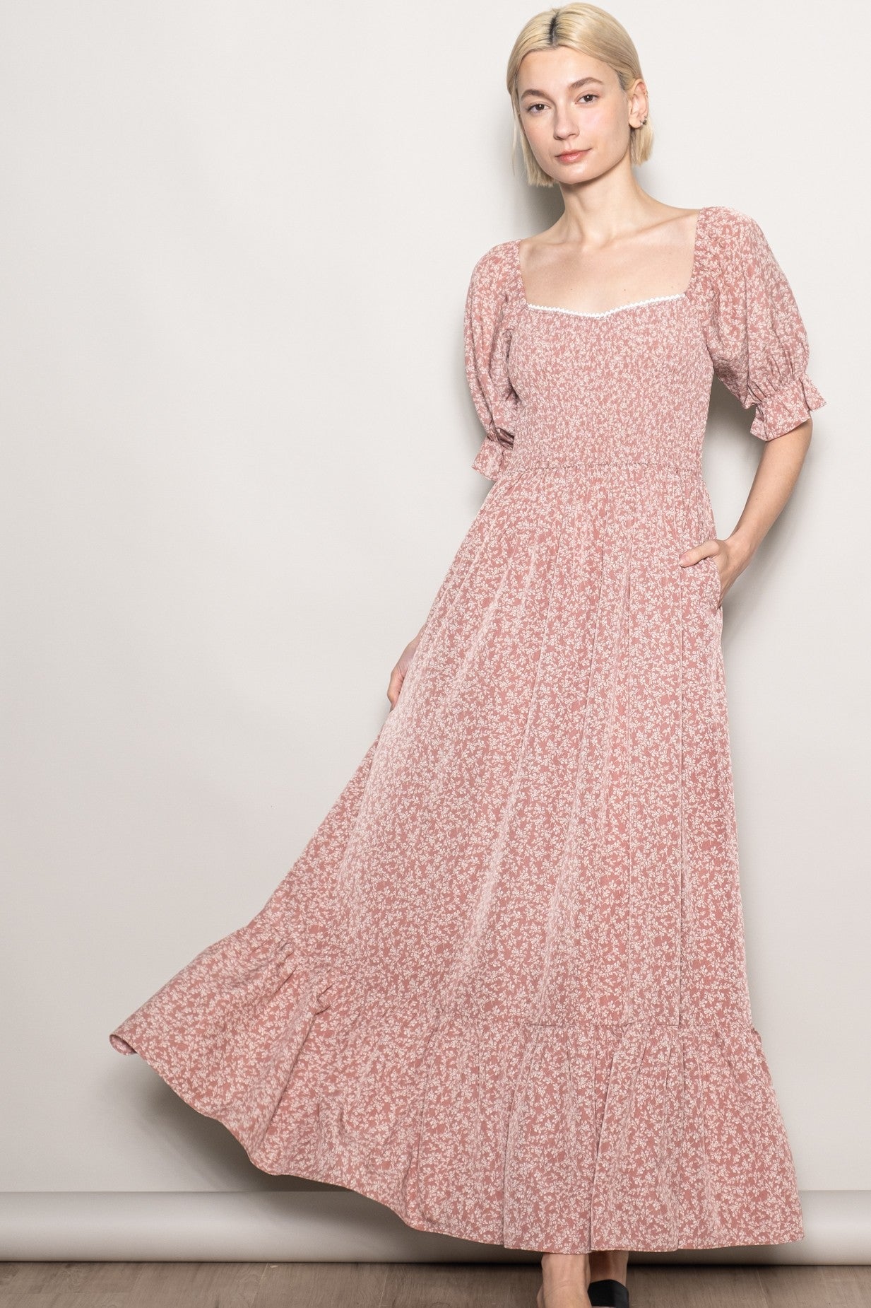 woman wearing a pink floral maxi dress with puff sleeves and a ruffled hem