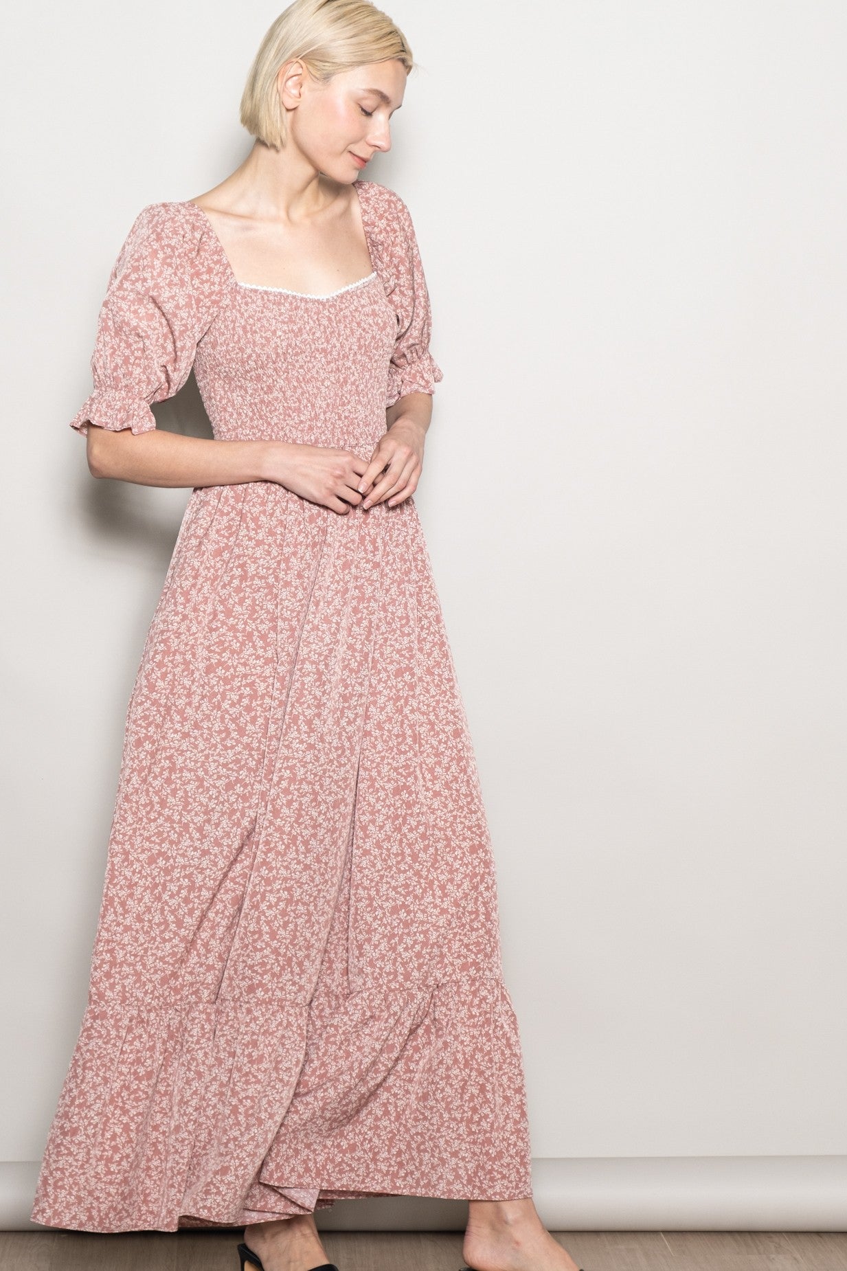 woman wearing a pink floral maxi dress with puff sleeves and a square neckline, standing against a neutral background