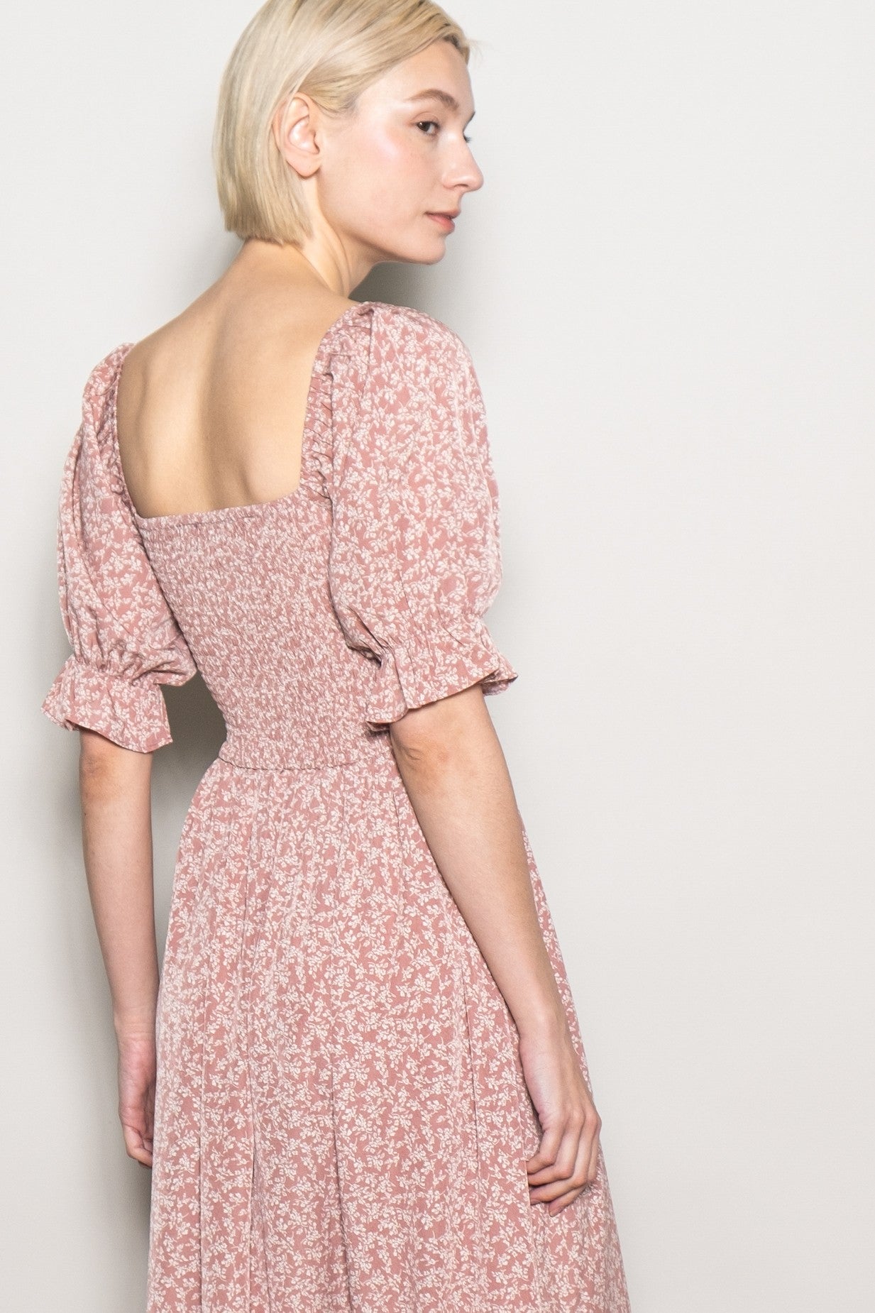 woman wearing a pink floral puff sleeve dress with a square back and fitted waist