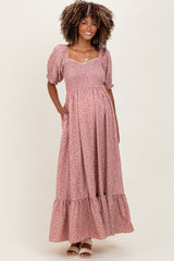 woman wearing a pink floral maternity maxi dress with puff sleeves and pockets, displaying her baby bump