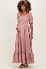 woman wearing a pink floral maternity maxi dress with puff sleeves and a flowing skirt, holding her baby bump