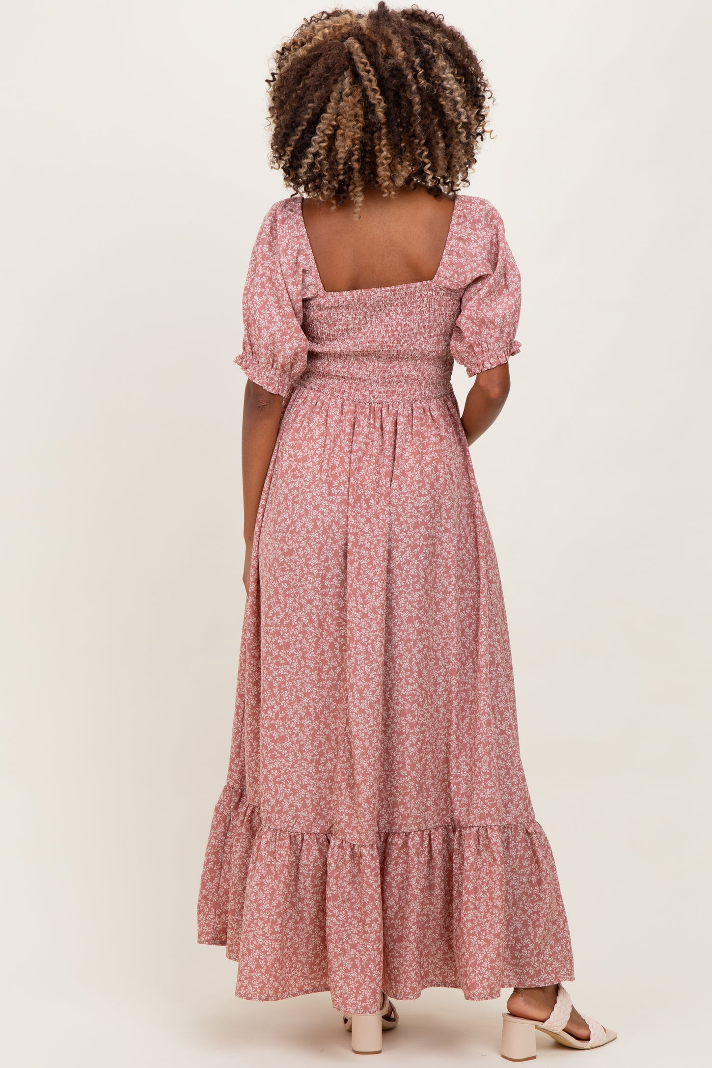 woman wearing a pink floral maternity maxi dress with puff sleeves and a tiered hem, showcasing a baby bump from the back
