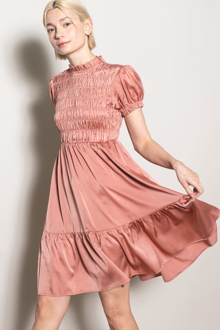 woman wearing a dusty rose puff sleeve dress with a smocked bodice and a flared skirt