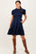woman wearing a navy blue smocked short sleeve dress with pockets, styled with brown knee-high boots