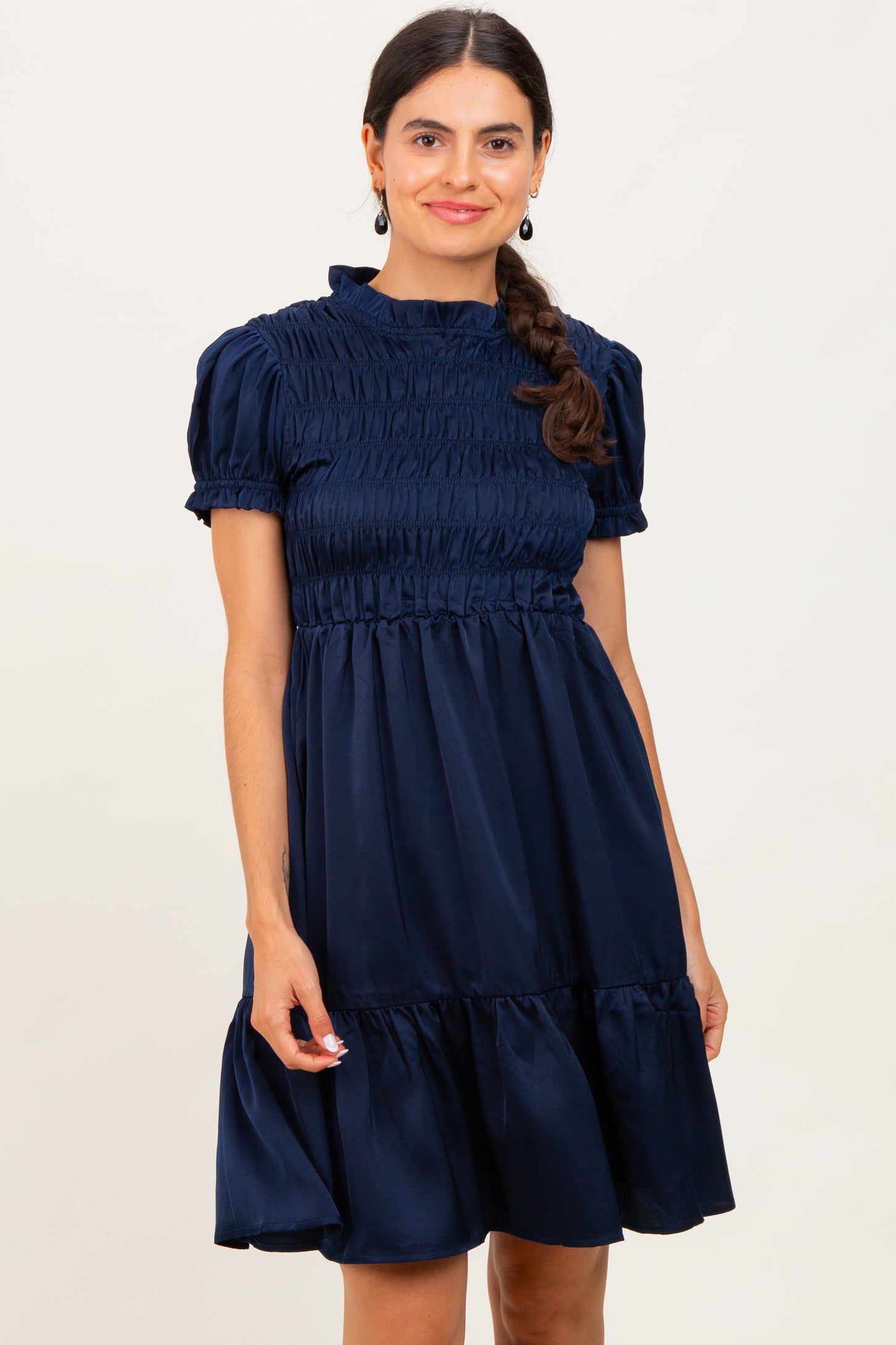 woman wearing a navy blue short sleeve smocked dress with a tiered skirt and a relaxed fit