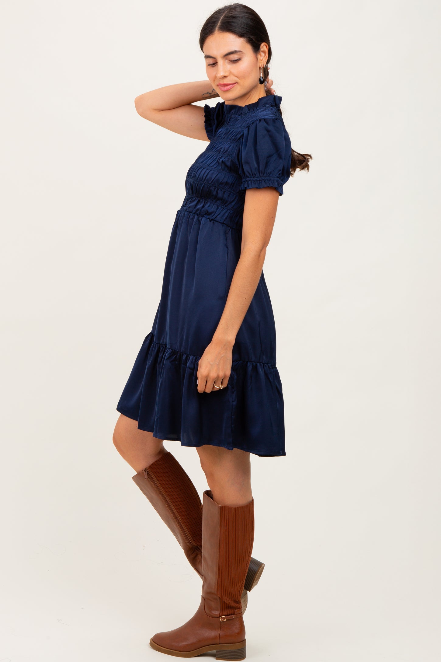 woman wearing a navy blue short sleeve smocked dress with a tiered skirt and brown knee-high boots