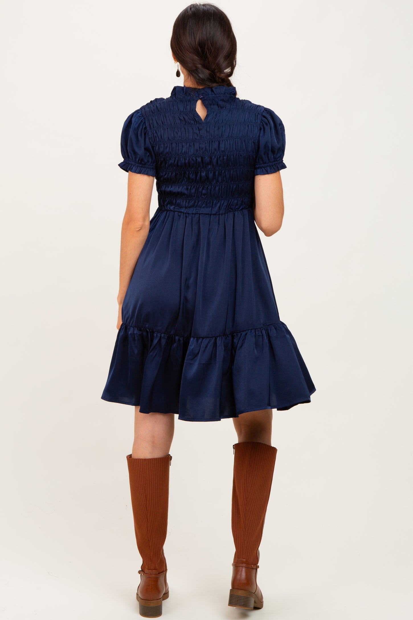 woman wearing a navy blue smocked dress with short puff sleeves and a tiered skirt