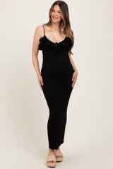 woman wearing a black ribbed maternity dress with ruffle details and adjustable straps, showing her baby bump