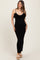 woman wearing a black ribbed maternity dress with ruffle details and adjustable straps, showing her baby bump