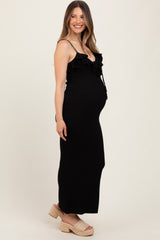 woman wearing a black maternity maxi dress with ruffle details and a visible baby bump, standing sideways