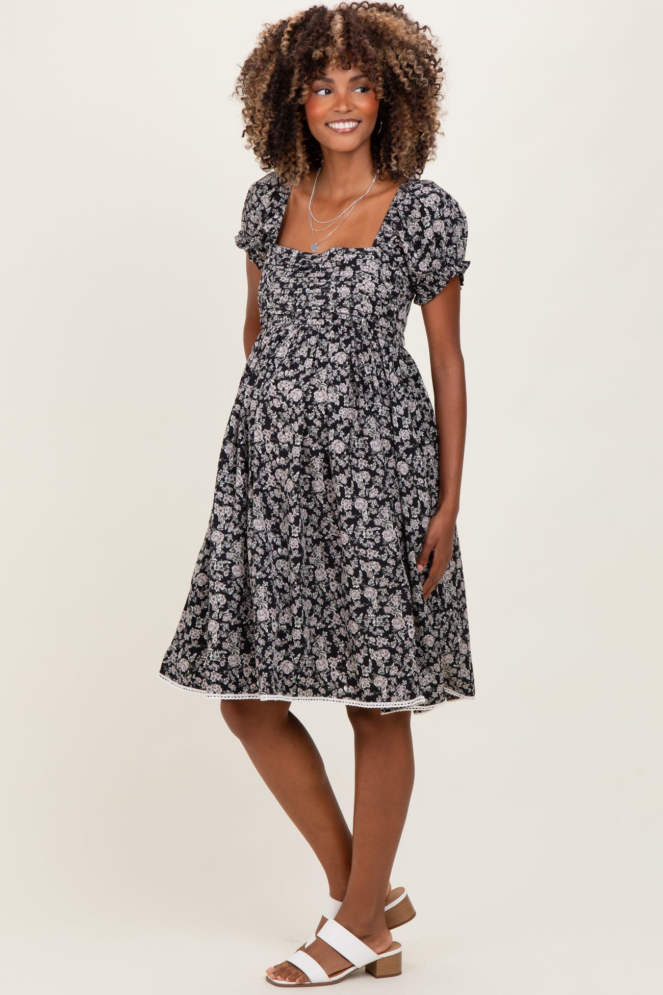 woman wearing a black floral maternity dress with puff sleeves and a baby bump visible