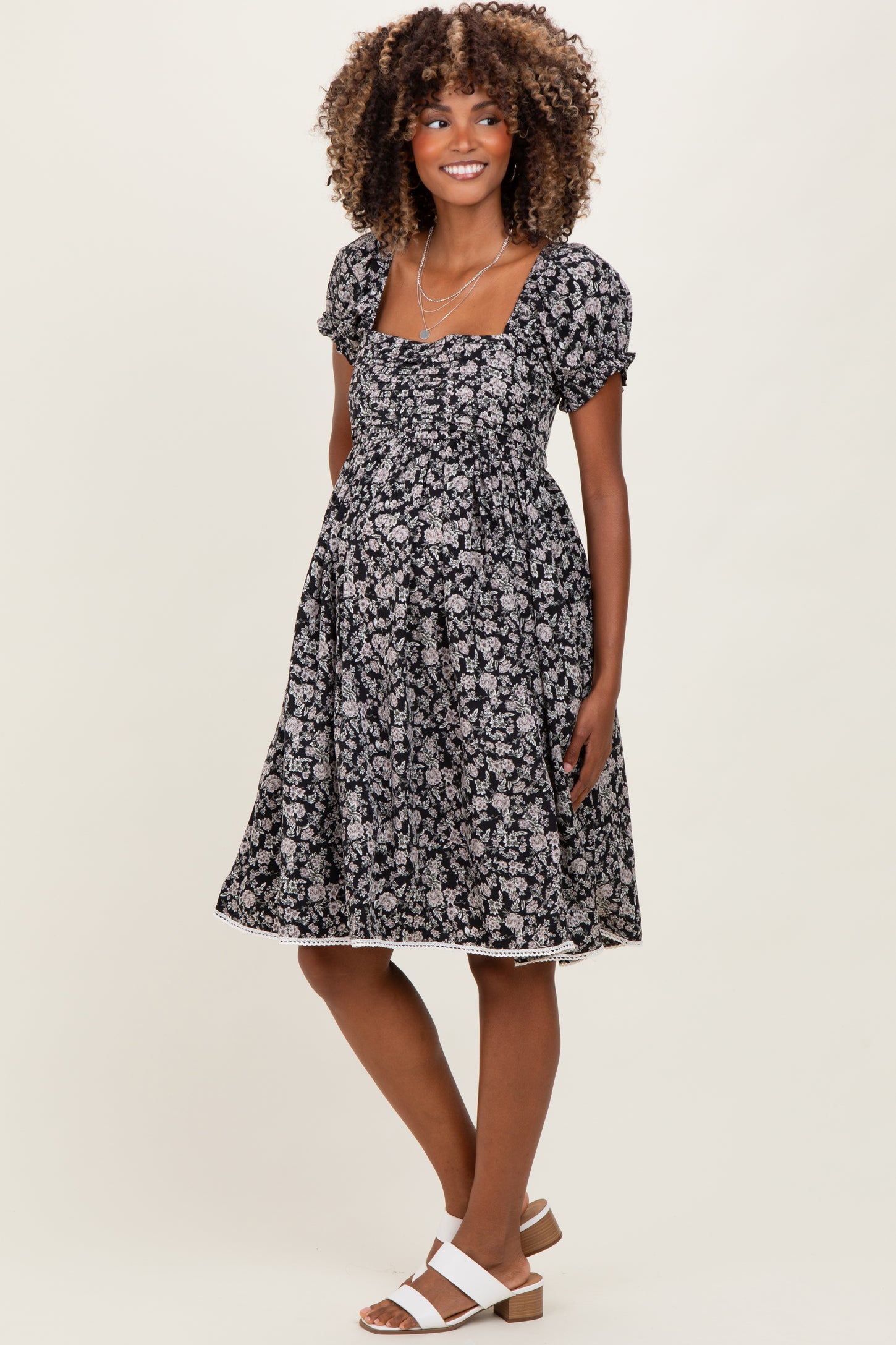 woman wearing a black floral maternity dress with puff sleeves and a baby bump visible