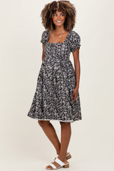 woman wearing a black floral maternity dress with puff sleeves and a baby bump visible