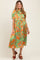 woman wearing a green floral maternity dress with short sleeves and a tie waist, showcasing her baby bump